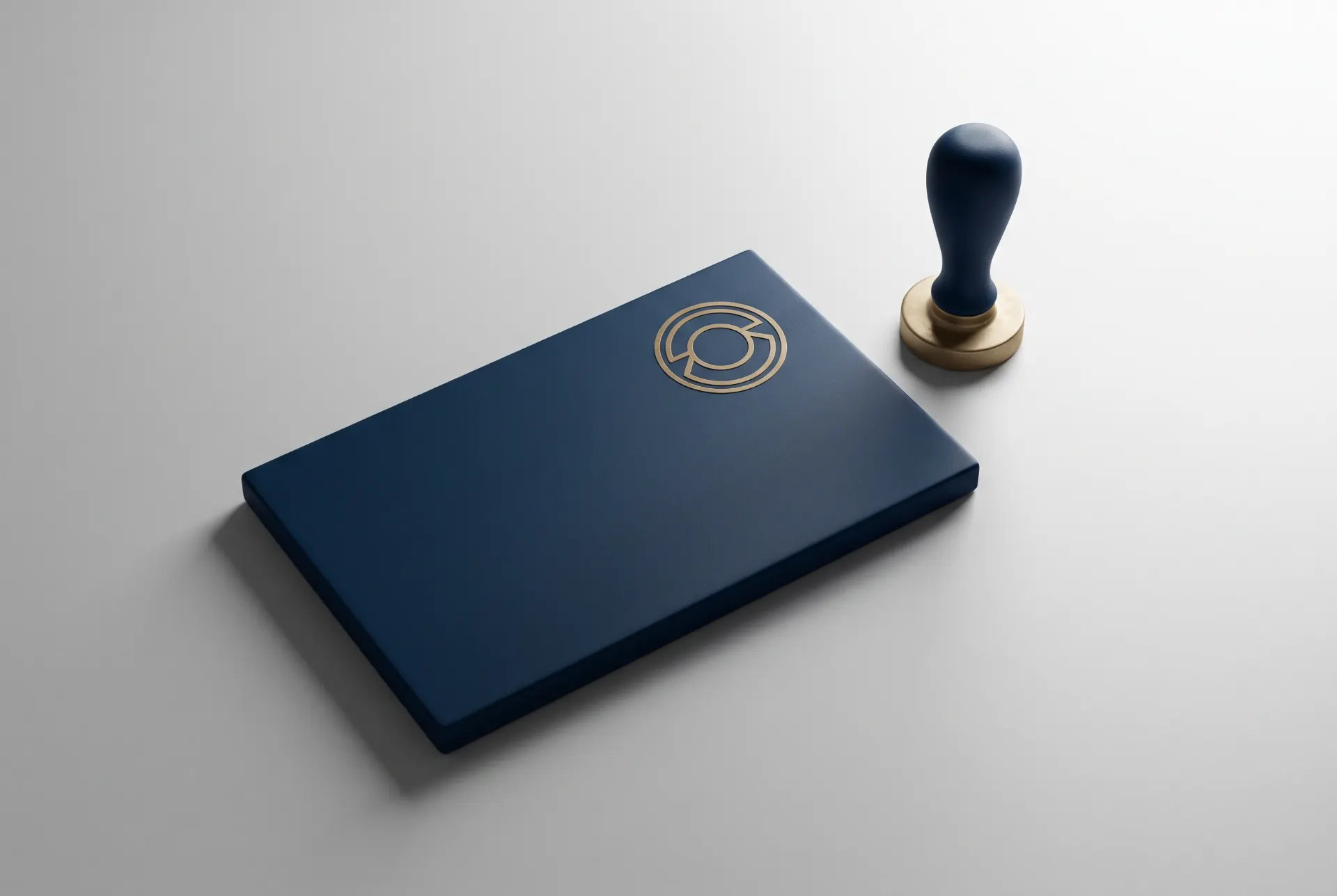 Placa de papelaria azul-escura com ícone circular em relevo, ao lado de um carimbo com cabo azul e base de madeira sobre fundo claro, evidenciando marcação e identificação