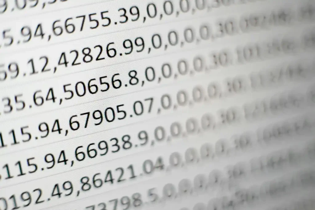 Imagem em close de números e códigos na tela, com dados em formato decimal e elementos de programação desfocados ao fundo, sugerindo análise de dados.